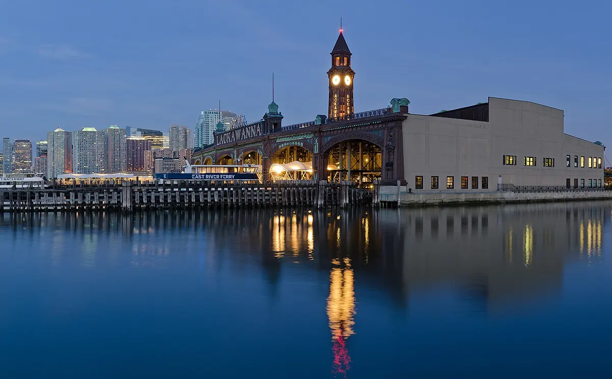 Hoboken Terminal and its clock tower at dusk, reflected in the Hudson