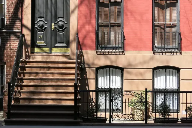A brownstone stoop with iron railings and a paneled front door