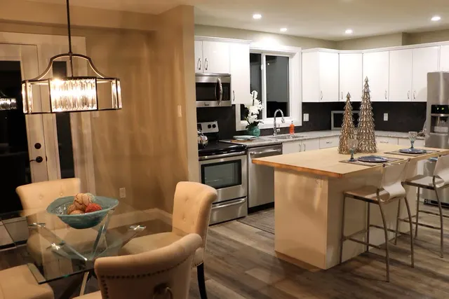 An open kitchen with a long island, pendant lights and white cabinets